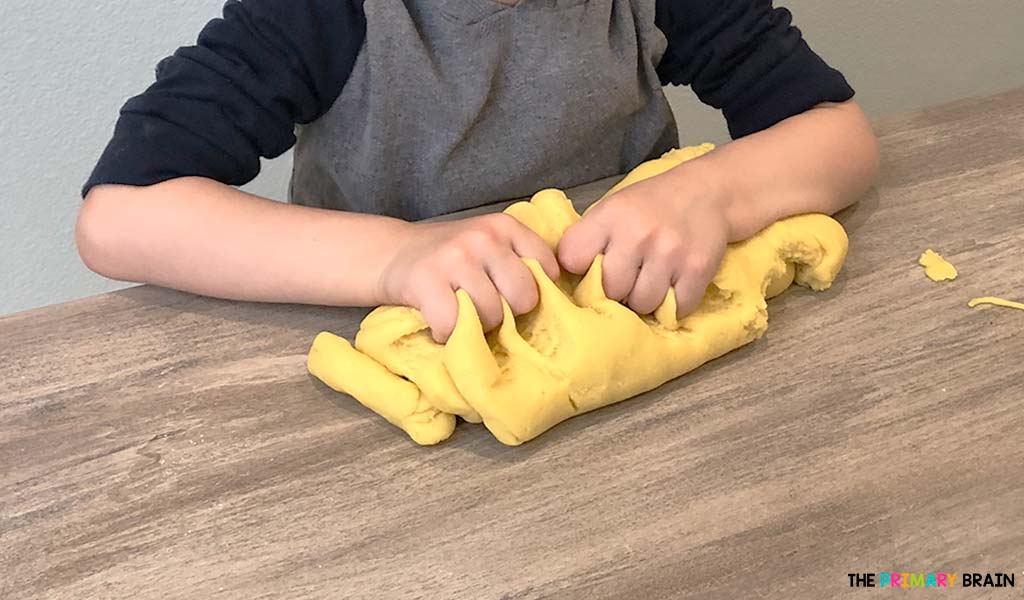 A childs hands kneading yellow playdough