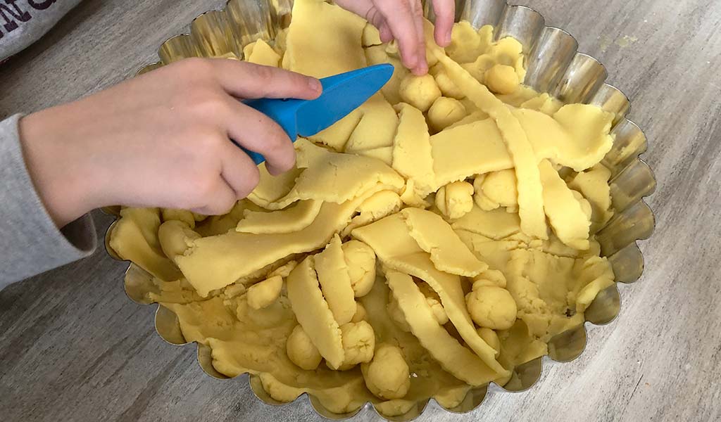 Forming yellow playdough into a pie tin